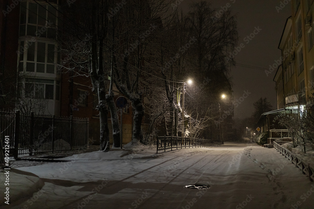 a night blizzard in the city, a quiet deserted park in the light of lanterns, a winter landscape of a quiet street