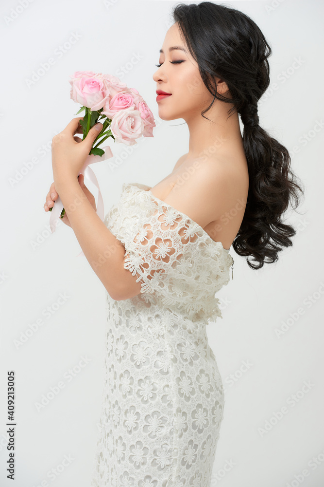 Young beautiful woman in a white dress posing with a bouquet of roses Young beautiful woman in a white dress posing with a bouquet of roses