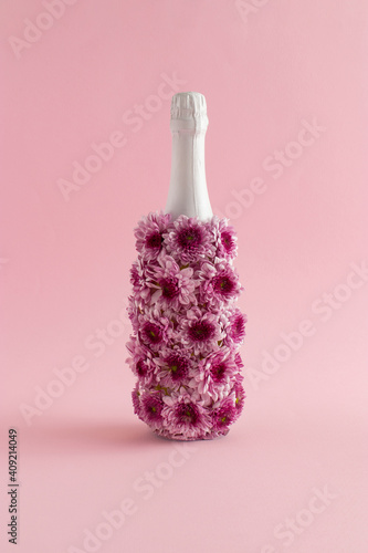 A creative love concept with a bottle of champagne made of flowers on a pink background. Valentines or woman's day idea