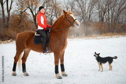 A girl rider trains riding on her horse in the snowy winter.