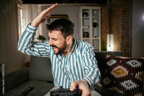 Young attractive man playing video games in the living room. Handsome man having fun at home.