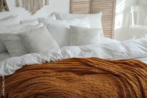 Canvas Print Warm orange knitted plaid on bed indoors