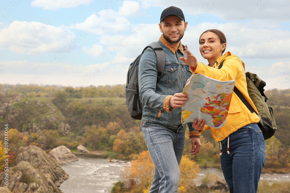 Couple of travelers with backpacks and map enjoying beautiful view near mountain river. Autumn vacation Couple of travelers with backpacks and map enjoying beautiful view near mountain river. Autumn vacation