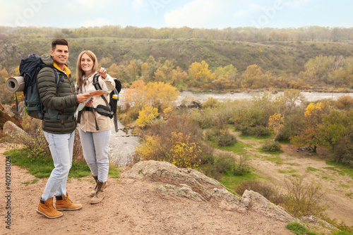 Couple of travelers with backpacks and map enjoying beautiful view near mountain river. Autumn vacation