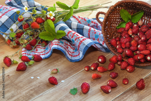 Fresh wild strawberry in a basket on a wooden table. Rustic style.