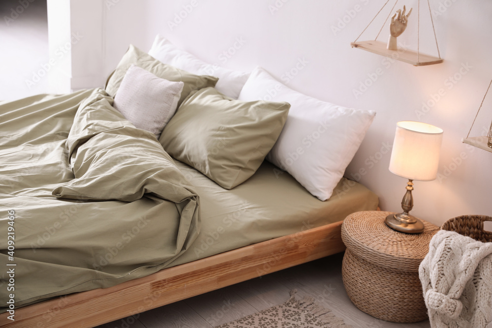 Comfortable bed with olive green linen in modern room interior - obrazy, fototapety, plakaty 
