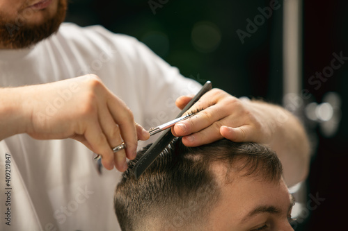 Fresh style. Close up of client of master barber, stylist during getting care and new look of hairstyle. Professional occupation, male beauty and self-care concept. Soft colors and focus, vintage.