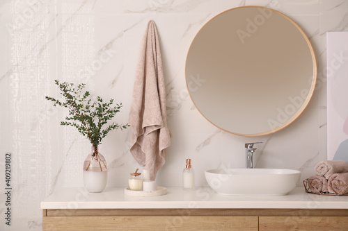 Fotografija Vase with beautiful branches and fresh towels near vessel sink in bathroom