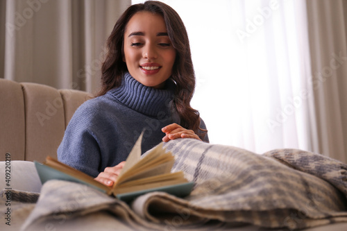 Young woman reading book at home. Winter atmosphere