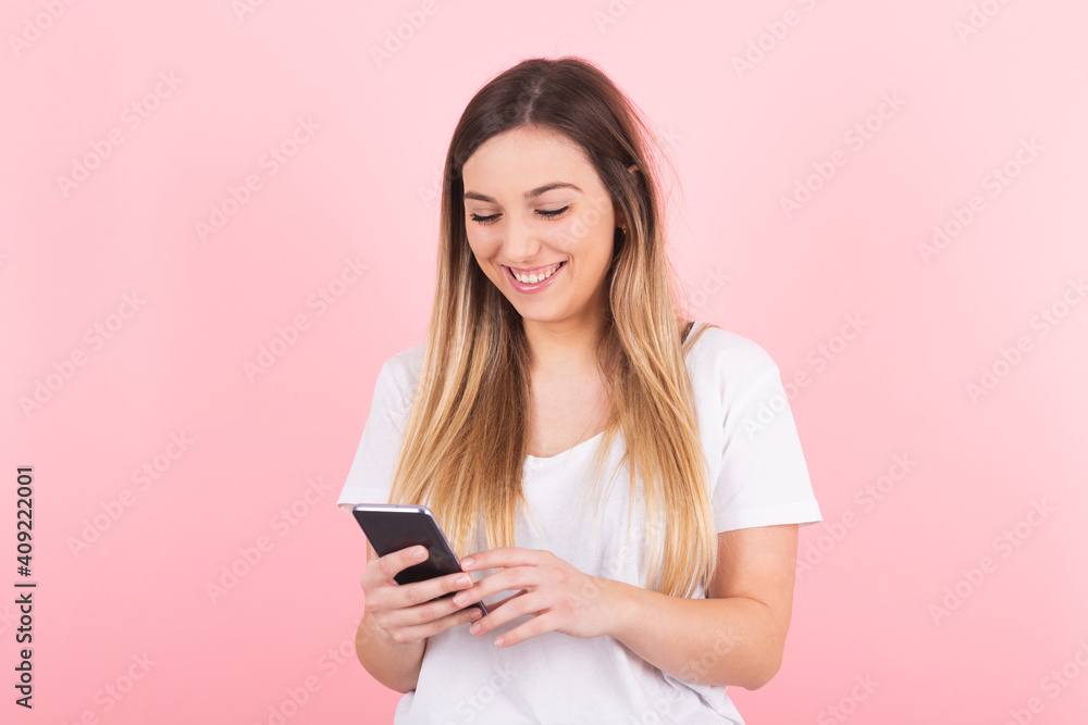 a young blonde woman smiles happily looking at her cell phone a young blonde woman smiles happily looking at her cell phone