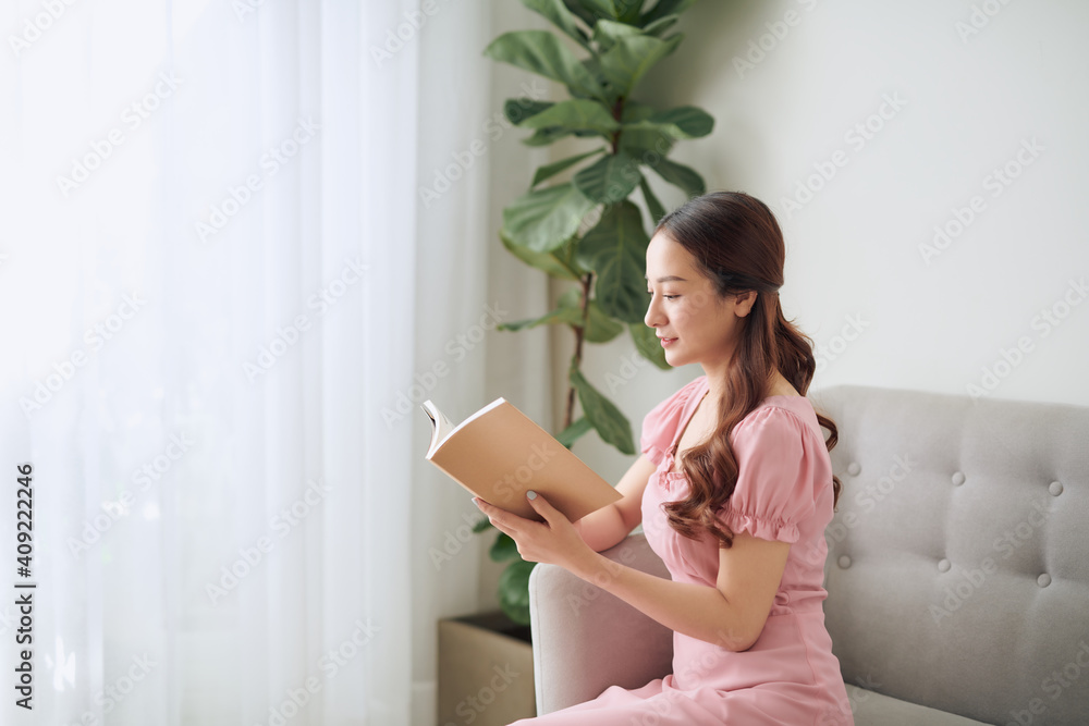 leisure, literature and people concept - smiling Asian woman reading book at home leisure, literature and people concept - smiling Asian woman reading book at home