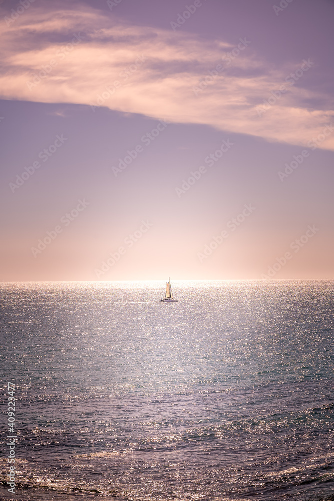 Lone yacht in the pink sky and sea