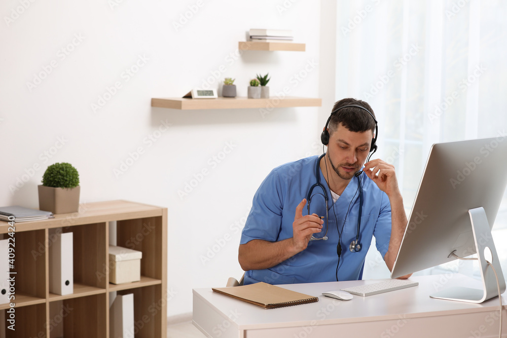 Doctor with headset consulting patient online at desk in clinic, space for text. Health service hotline Doctor with headset consulting patient online at desk in clinic, space for text. Health service hotline