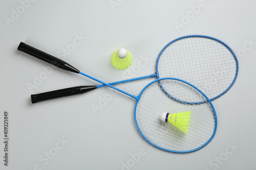Rackets and shuttlecocks on light grey background, flat lay. Badminton equipment