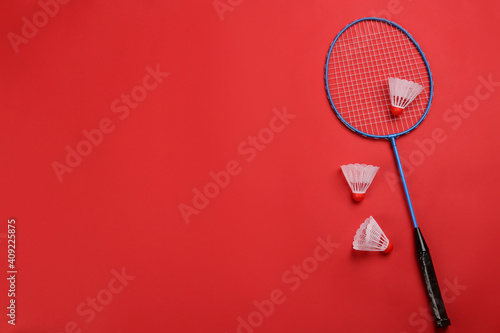 Racket and shuttlecocks on red background, flat lay with space for text. Badminton equipment © New Africa