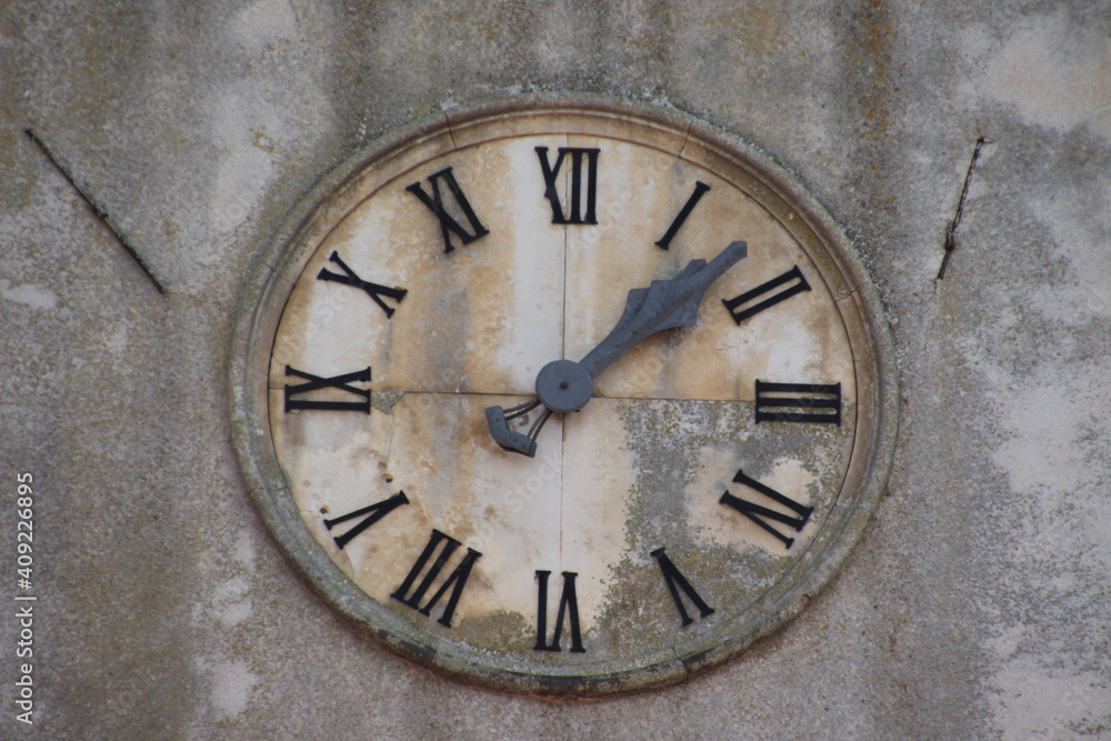 Ancient clock on the old and rustic wall background