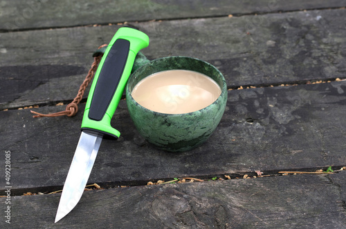 Knife with a green handle and a green mug. Wooden background. photo