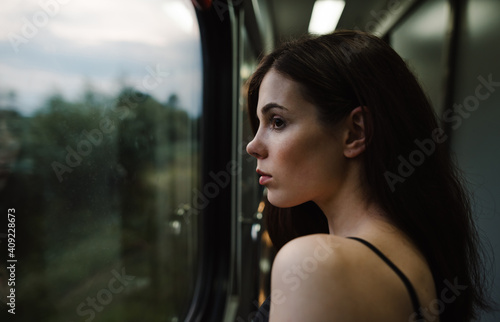 Attractive lady looks out the train window with a pensive face on a beautiful evening landscape. Travel by train Free Download Attractive lady looks out the train window with a pensive face on a beautiful evening landscape. Travel by train - GFXLoad