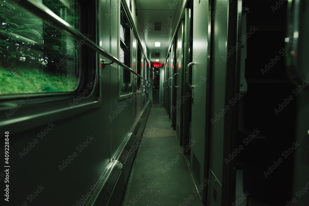 Obraz premium Interior of a train corridor. Evening photo of a compartment train. Empty train car on the road. Railway concept.