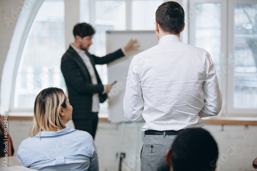 Explaining. Male speaker giving presentation in hall at university workshop. Audience or conference hall. Rear view of unrecognized participants. Scientific  business event  training. Education