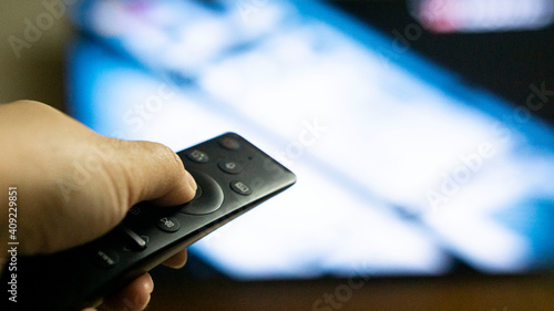 Closeup of a hand holding a remote control for the television