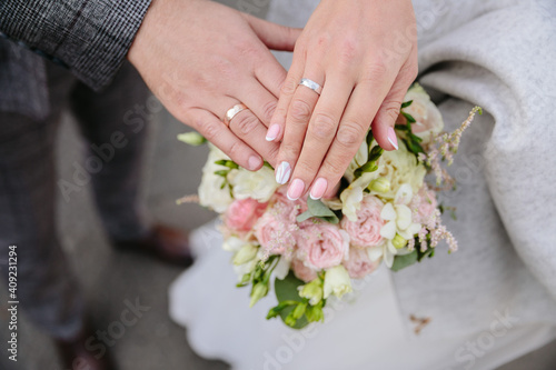 Holding hands with wedding rings. Bridal bouquet is held with bridal hands. Invitation to the wedding ceremony. Wedding rings. Flowers and shoes for the bride. Bridal shoes and jewellery