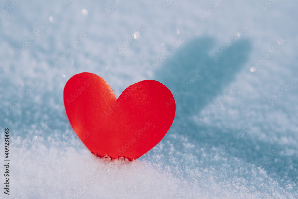 Lonely valentine. Red heart in cold, frosty morning snow. Valentine's Day greeting card. A symbol of love and romantic relationships. Congratulations on holiday of February 14. Copy space for text