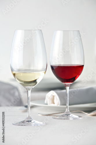 Ein Glas Rotwein und ein Glas Weißwein auf einem weiß gedeckten Tisch
