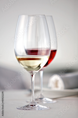Ein Glas Rotwein und ein Glas Weißwein auf einem weiß gedeckten Tisch