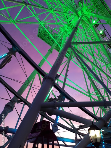 view from below of green-lighted ferris wheel with vanilla twilight background photo