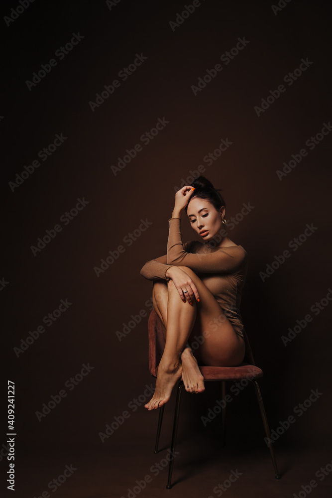 beautiful girl sitting on a chair on a dark brown background 