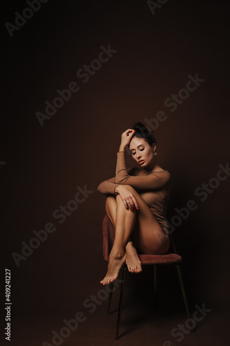 beautiful girl sitting on a chair on a dark brown background 