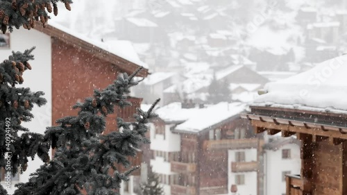 Snow falling on houses and connifers in the heart of the swiss village of Zermatt in the canton of Valais, Switzerland. photo