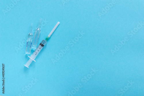 Bottle with vaccine and medicine syringe with vaccine on blue background. Concept of vaccination and healthcare.