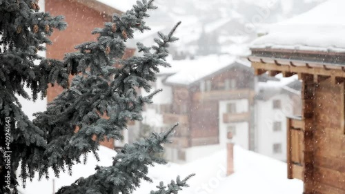 Snow falling on houses and connifers in the heart of the swiss village of Zermatt in the canton of Valais, Switzerland.