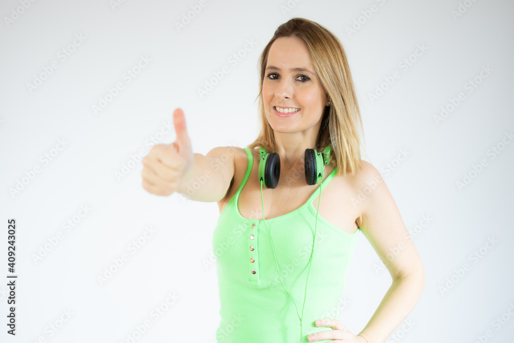 Young happy cheerful woman in headphones showing thumb up over white background. Young happy cheerful woman in headphones showing thumb up over white background.