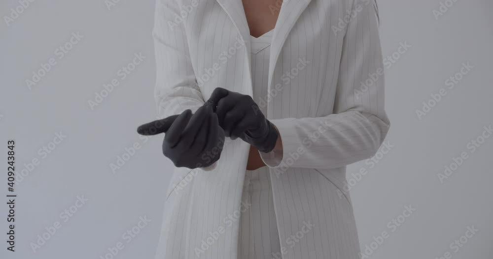 Beautician puts on black gloves for examining a girl lying on the bed.