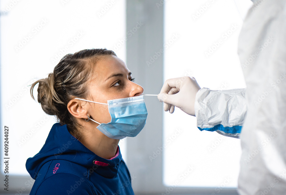 Healthcare worker with protective equipment performs  nasal swab on  girl. Nose swab for Covid-19 rapid test.
