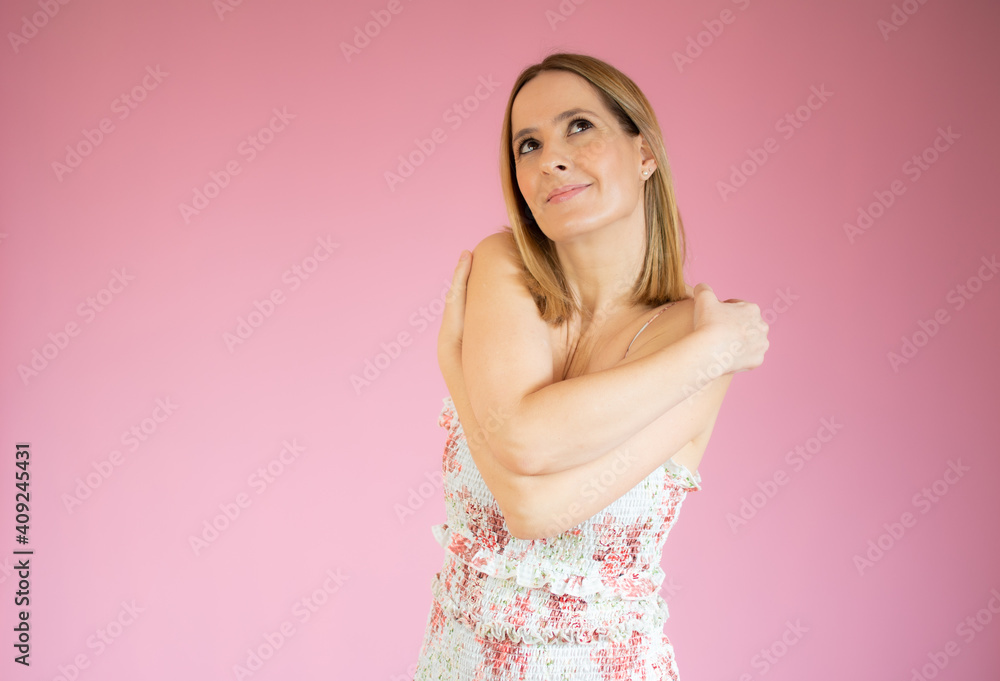 Portrait of a pretty young woman hugging herself while standing isolated over pink background Portrait of a pretty young woman hugging herself while standing isolated over pink background