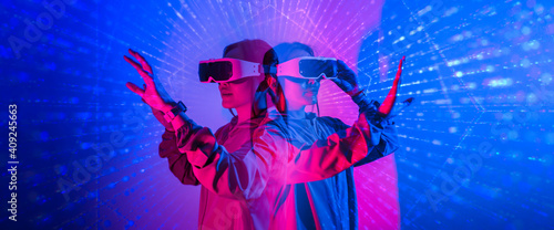 Young woman using glasses of virtual reality on dark background. Smartphone using with VR headset,virtual reality,future technology concept.Asian woman using VR glasses in colorful neon lights. photo