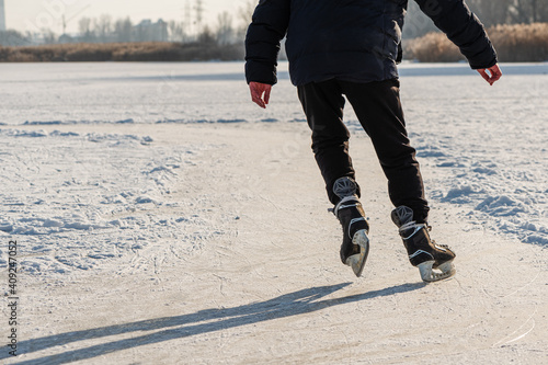 Obraz na płótnie Skater legs at skating rink. Man skating on white ice on frozen lake. Back view. Winter leisure activity. w salonie