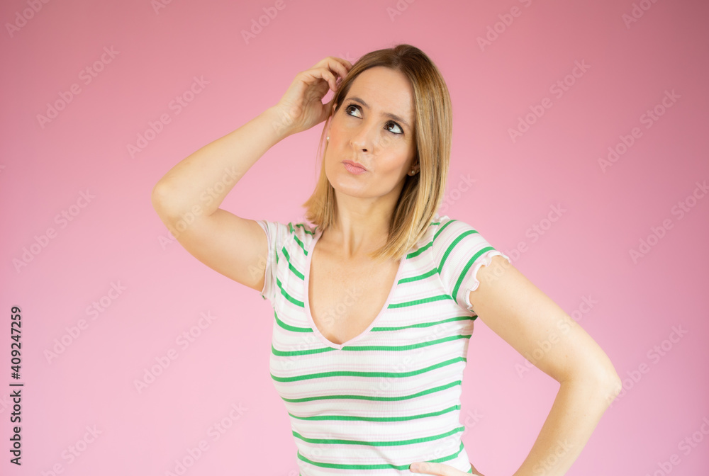 Happy young woman in striped t-shirt thinking over pink background.