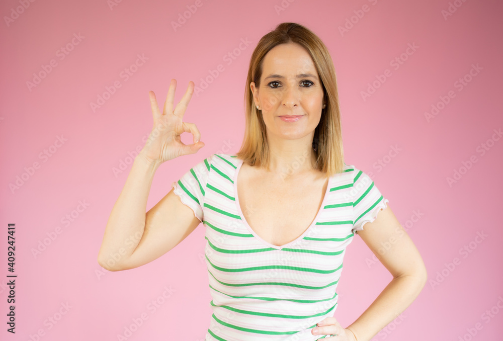 Happy young woman showing okay sign with fingers isolated over pink background Happy young woman showing okay sign with fingers isolated over pink background