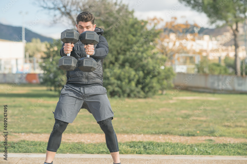 Fototapeta premium athletic man doing squat and back exercise and cross training with dumbbells