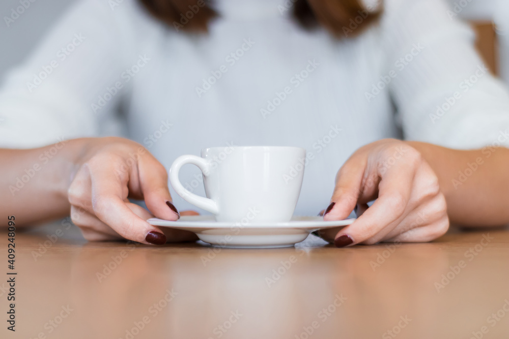 The woman on the wooden table holding Turkish coffee with your hands The woman on the wooden table holding Turkish coffee with your hands