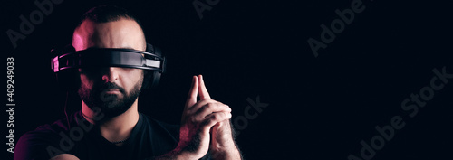 Young bearded hipster musician DJ listens to music on headphones and made his fingers in the form of pistol on black background. International DJ Day