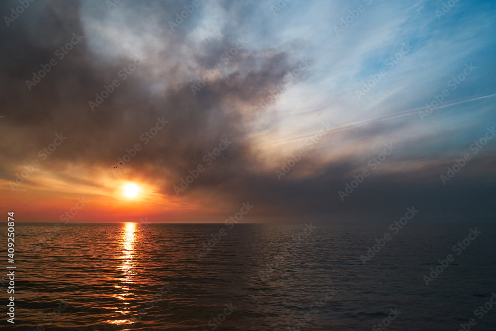 Sea sunset. Smoke wildfires sweeping across the sky.