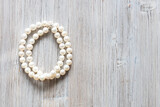 folded natural white pearl necklace on gray wooden background with copyspace