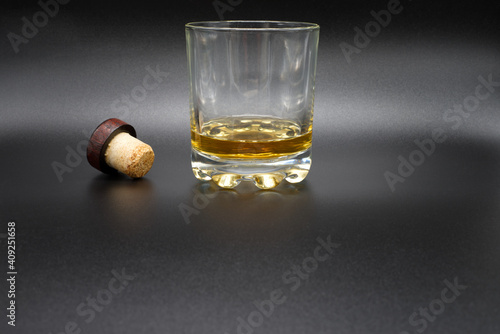a glass of whiskey with a cork stopper