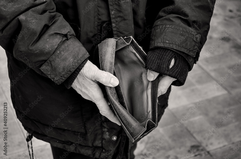 An elderly woman holds an empty purse or wallet on wooden vintage table. Black and white photo.The concept of poverty in retirement. Global Extreme poverty. No money help me. Global Financial crisis. An elderly woman holds an empty purse or wallet on wooden vintage table. Black and white photo.The concept of poverty in retirement. Global Extreme poverty. No money help me. Global Financial crisis.